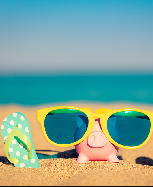 one flip flop and a piggy bank with sunglasses on a beach.