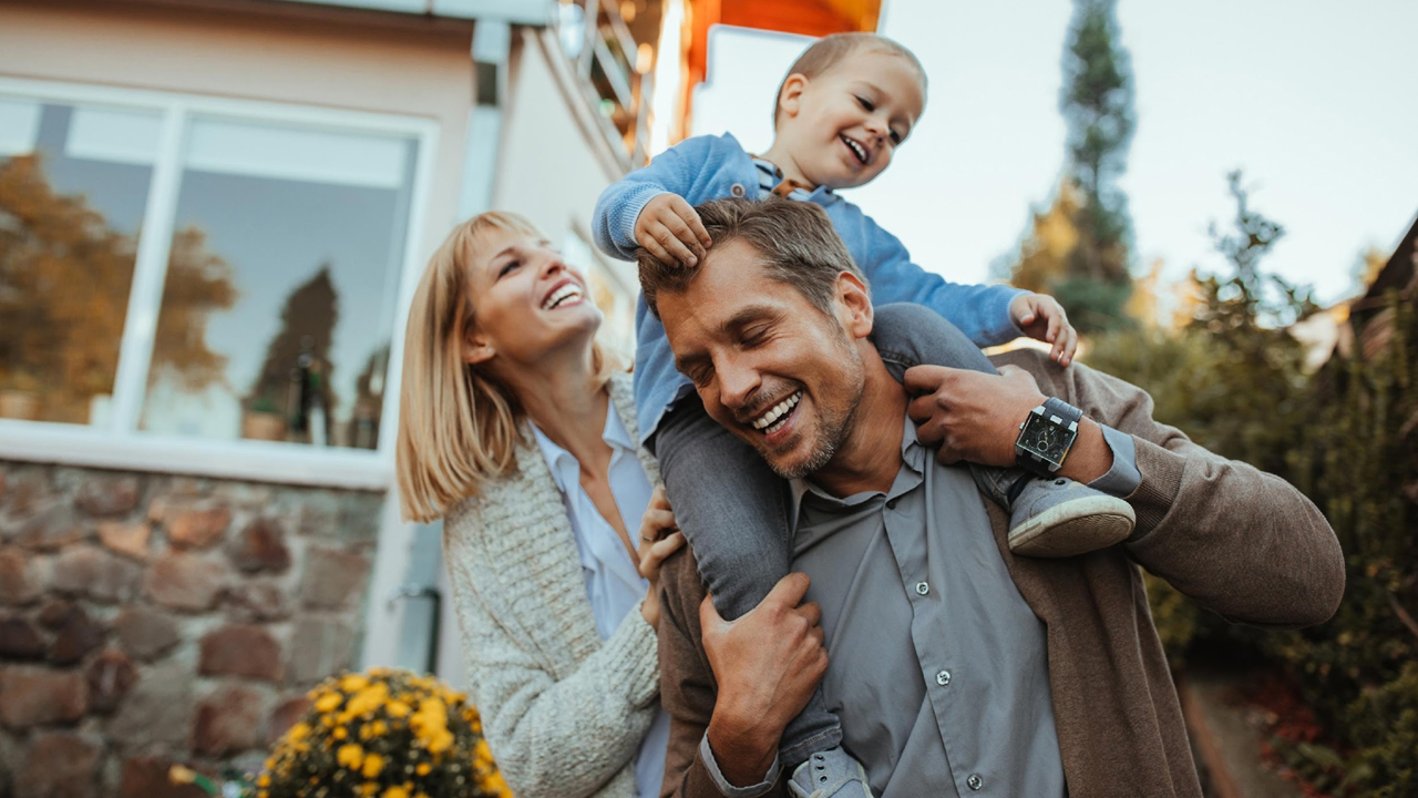Mom, dad and little boy, in front of house.