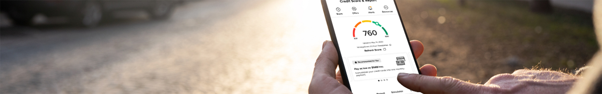 Man holding cell phone with credit score on screen.